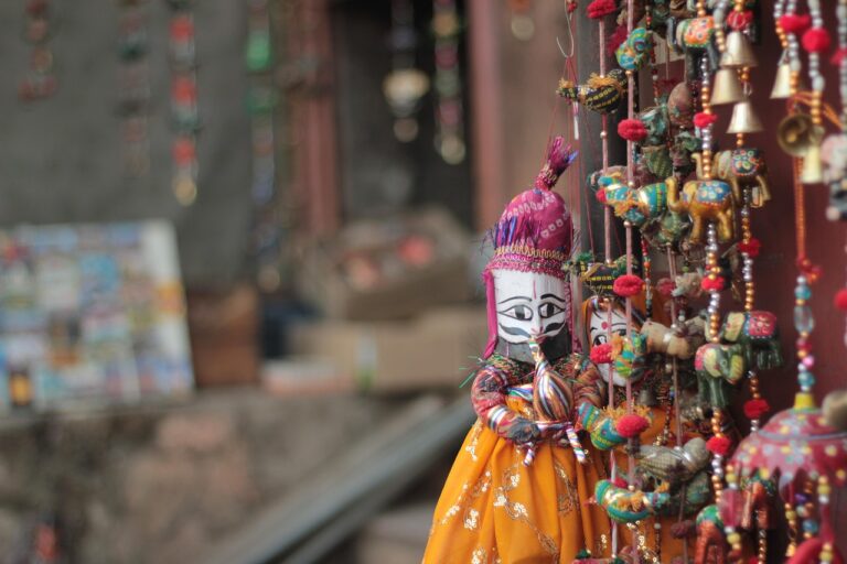 Colorful Rajasthani puppets and traditional handcrafted ornaments hanging in front of a trendy clothing store.